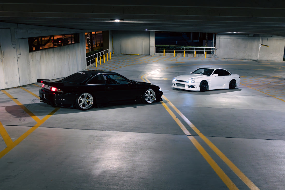 Black and white modified cars in a parking garage.